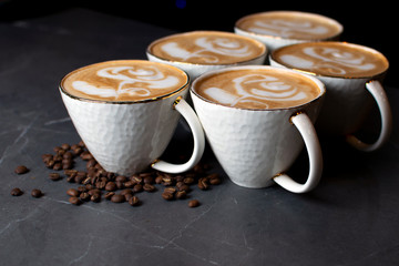 cups of coffee stand on a marble table in a coffee shop, latte art on coffee with coffee beans