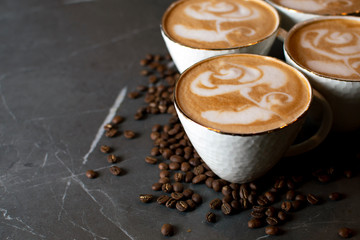 cups of coffee stand on a marble table in a coffee shop, latte art on coffee with coffee beans