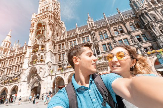 happy multinational couple in love hugs and takes a selfie photo on the background of The city hall tower in Munich. Honeymoon trip to Germany
