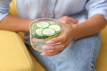 Woman with glass of healthy infused water at home, closeup
