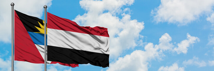 Antigua and Barbuda with Yemen flag waving in the wind against white cloudy blue sky together. Diplomacy concept, international relations.