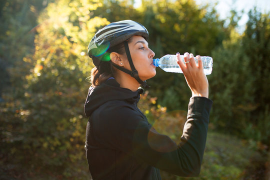 Female cyclist drinking water from bottle
