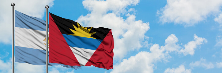 Argentina and Antigua and Barbuda flag waving in the wind against white cloudy blue sky together. Diplomacy concept, international relations.