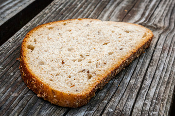 A slice of country bread with sunflower seeds lies on a table
