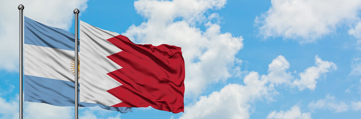 Fototapeta premium Argentina and Bahrain flag waving in the wind against white cloudy blue sky together. Diplomacy concept, international relations.