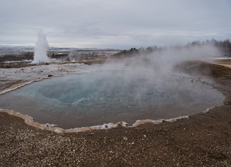 Kochendes Thermalwasser mit Geysir im Hintergrund