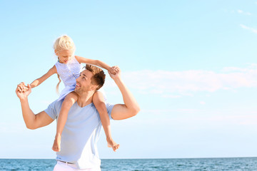 Portrait of happy father with daughter on sea beach
