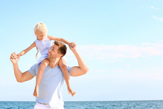 Portrait of happy father with daughter on sea beach