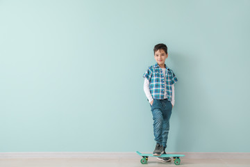 Cute fashionable boy with skateboard against color wall © Pixel-Shot