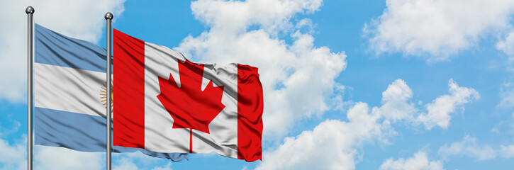 Argentina and Canada flag waving in the wind against white cloudy blue sky together. Diplomacy concept, international relations.