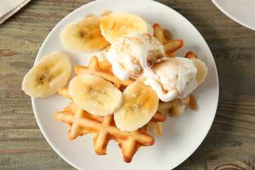 Plate with tasty waffles, ice cream and banana on table