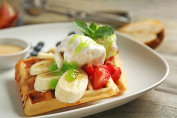 Tasty waffles, ice cream and fruits on plate, closeup