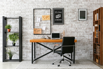 Comfortable workplace with mood board near brick wall