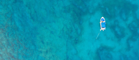 An aerial view of a boat in  the beautiful Mediterranean sea, where you can se the rocky textured...