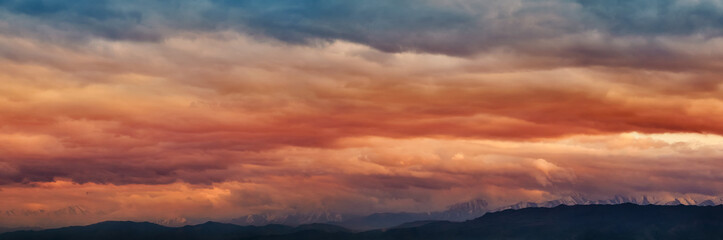 Dramatic light through the clouds against the backdrop of an exciting, vibrant stormy sky at sunset, dawn in the mountains. panorama, natural composition