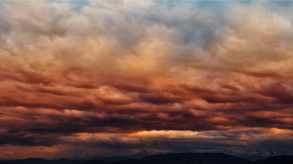 Dramatic light through the clouds against the backdrop of an exciting, vibrant stormy sky at sunset, dawn in the mountains. panorama, natural composition