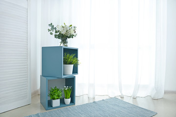 Shelf unit with houseplants near window in room