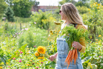 happy woman in overalls gardening outside in bright sunlight