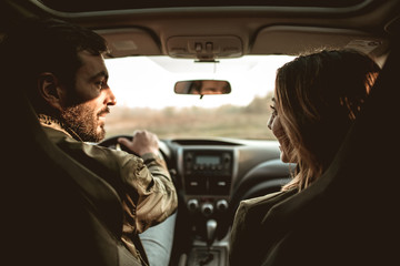 Young couple sitting on front passenger seats and looking at each other.