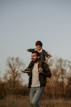 Father giving son ride on his shoulders during countryside walk.