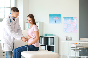 Gynecologist taking measurements of woman's belly in clinic