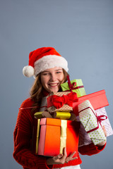 Joyful woman woman holding a lot of boxes with gifts on a gray background.