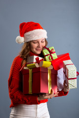 Picture of cheerful santa helper girl with many gifts box isolated on gray background