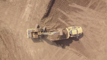 Large track hoe excavator filling a dump truck with rock and soil for fill at a new development construction project.