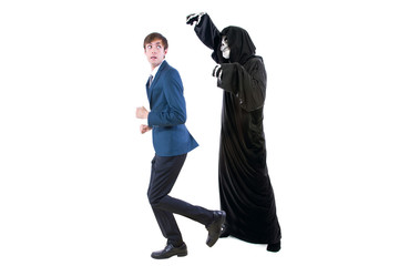 Man in a Halloween grim reaper ghost costume chasing, mocking and making fun of scared businessman...