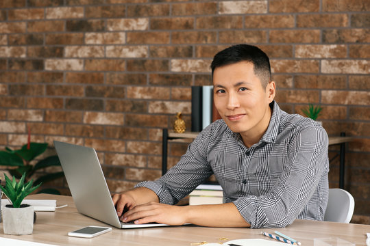 Asian programmer working on laptop in office
