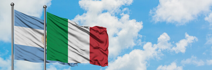 Obraz premium Argentina and Italy flag waving in the wind against white cloudy blue sky together. Diplomacy concept, international relations.