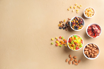 Bowls with different dried fruits and nuts on color background