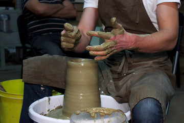 experienced potter makes a large vase on a potter's wheel. clay product. hands of a potter. reportage shooting.