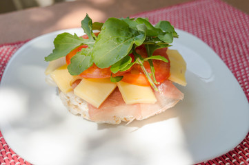 Rice cracker with raw ham, tomato and arugula and cheese.
