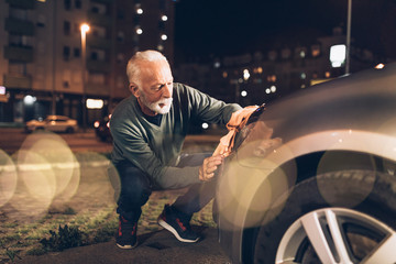 Obraz na płótnie Canvas Senior man washing his car in the evening at car wash station.