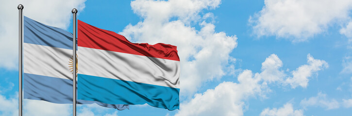 Fototapeta na wymiar Argentina and Luxembourg flag waving in the wind against white cloudy blue sky together. Diplomacy concept, international relations.