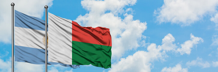Obraz premium Argentina and Madagascar flag waving in the wind against white cloudy blue sky together. Diplomacy concept, international relations.