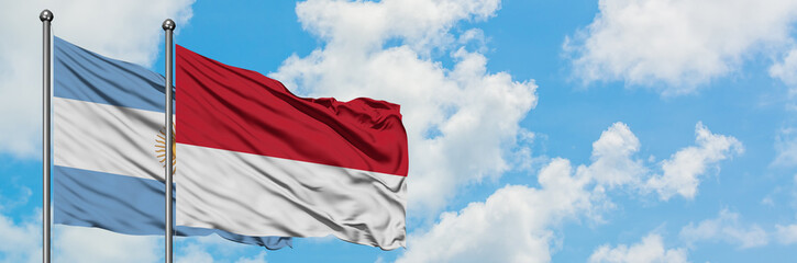 Argentina and Monaco flag waving in the wind against white cloudy blue sky together. Diplomacy concept, international relations.