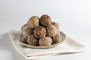 Homemade energy balls with dried apricots, raisins, dates, prunes, walnuts, almonds and coconut. Healthy sweet food. Energy balls in a plate on a white background