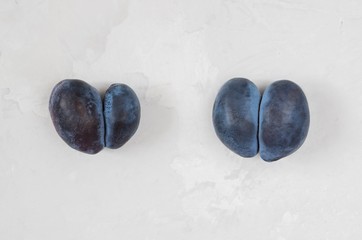 Trendy ugly food concept. Two purple plums on a gray background. Fruit with heart shape. The problem of food waste