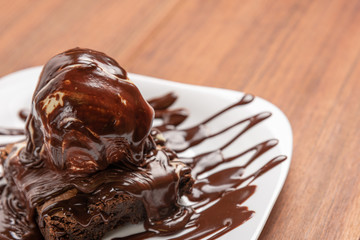 Chocolate Brownie with Vanilla Ice Cream and chocolatel syrup isolated on wooden background