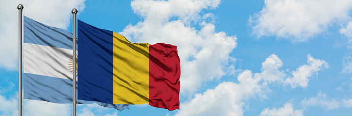 Obraz premium Argentina and Romania flag waving in the wind against white cloudy blue sky together. Diplomacy concept, international relations.