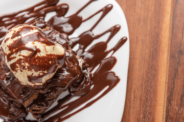 Chocolate Brownie with Vanilla Ice Cream and chocolatel syrup isolated on wooden background