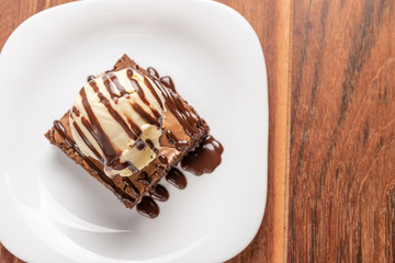 Chocolate Brownie with Vanilla Ice Cream and chocolatel syrup isolated on wooden background