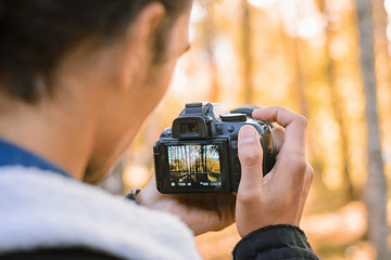 Passionate nature photographer shooting photos and videos in autumn forest, using his modern...