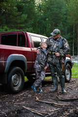Happy hunter with his son near their pickup truck before hunting in a forest © romankosolapov