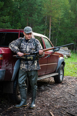 Hunter wearing glasses and camouflage with weapon shotgun at the outdoor hunting