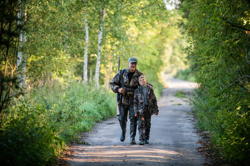 Father and son together hunting together. Walking the road in a forest.