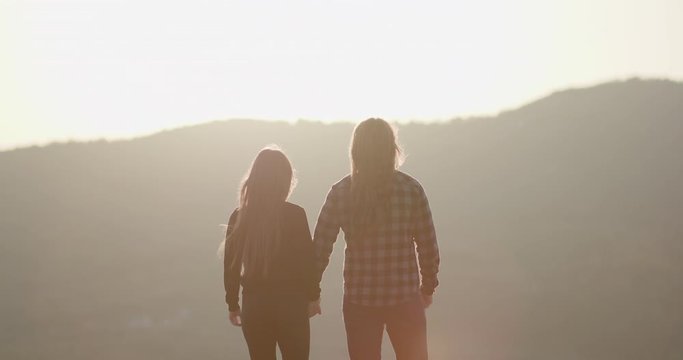Romantic couple at sunset holding hands in slow motion. Concept of love and happiness. Hands held together with sunlight flare in the background