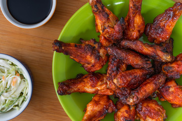 BBQ CHICKEN WINGS, SERVED WITH SALAD OF CABBAGE, IN GREEN PLATE AND YELLOW BACKGROUND